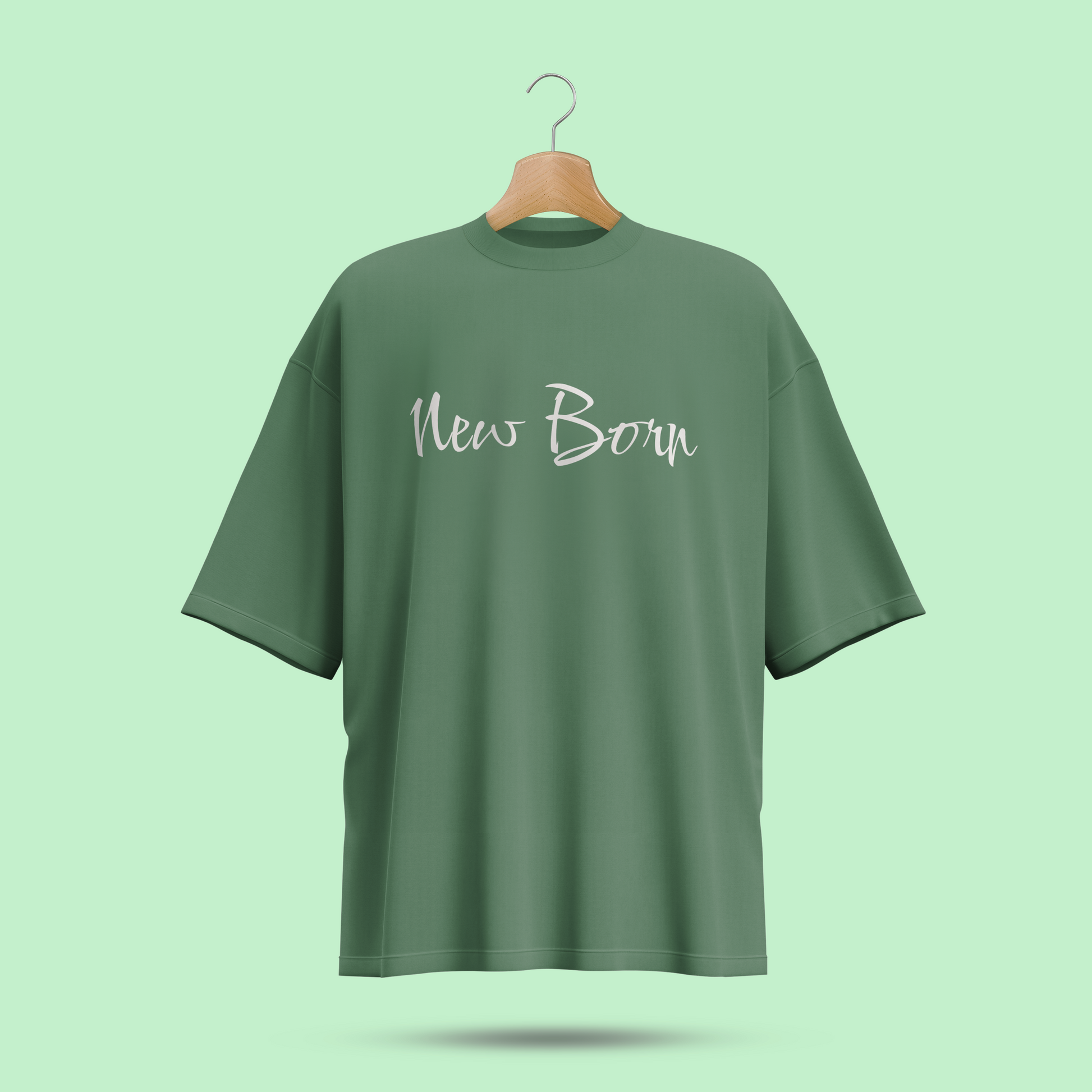 Green oversize t-shirt with 'New Born' text on a hanger against a light green background